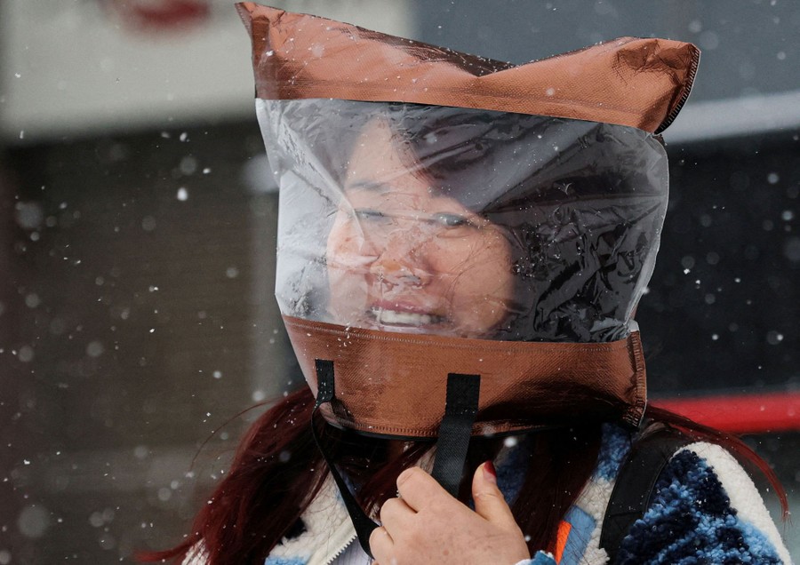 A woman wears a plastic bag over her head during a snowfall.