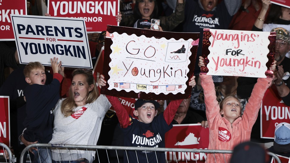 People holding signs reading "Parents for Youngkin," "Go Youngkin," and "Youngins for Youngkin"