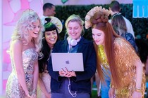 Greta Gerwig and members of the cast of Barbie looking at a laptop