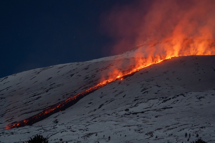 Lava flows down a snow-covered slope.