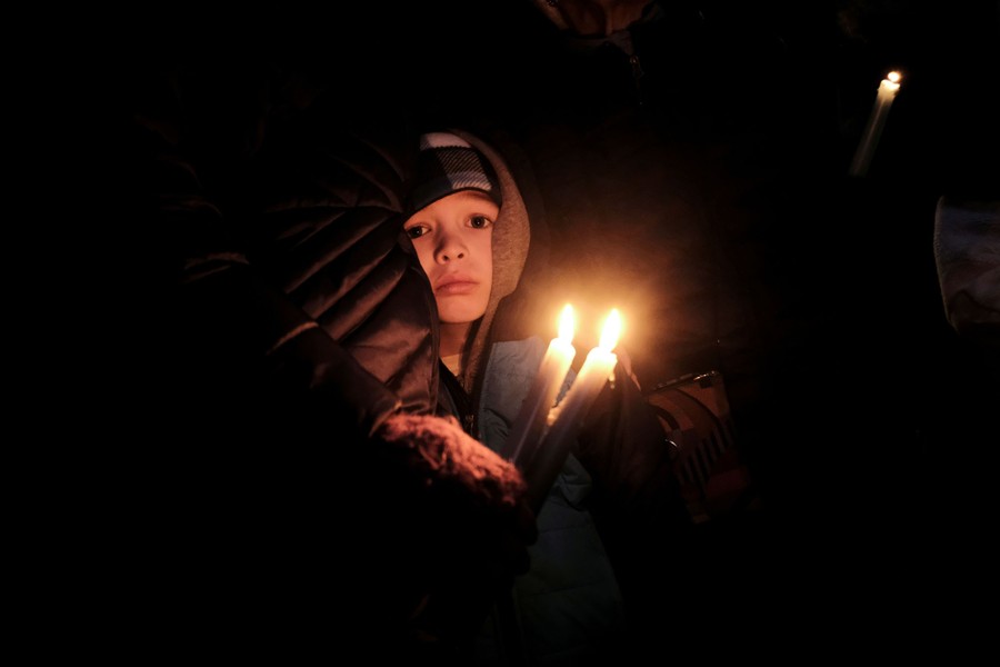 A child is held by an adult as they carry candles during a vigil.
