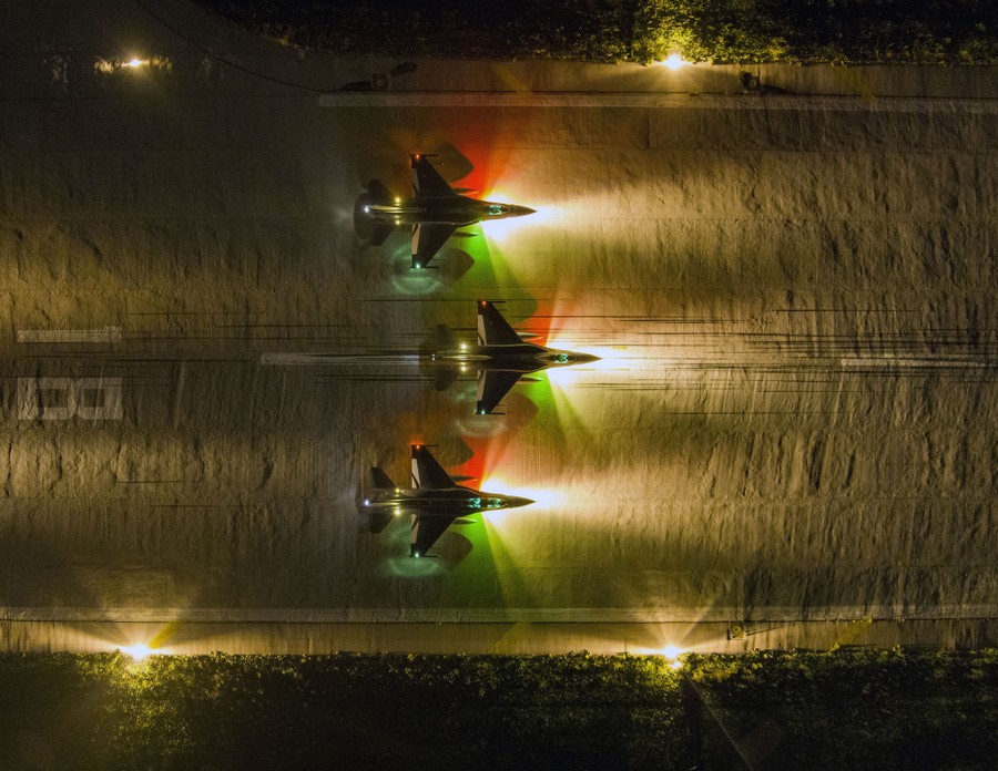 An aerial view of several fighter aircraft on a runway at night