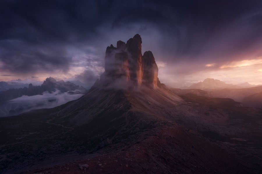 Tall spires of a stone mountain, seen among dark clouds