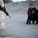 Guatemalan migrant Ledy Perez embraces her son Anthony on a dirt road as a member of the Mexican National Guard stands beside them.