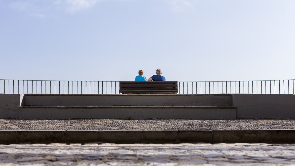 A couple sitting on a bench looking at the water