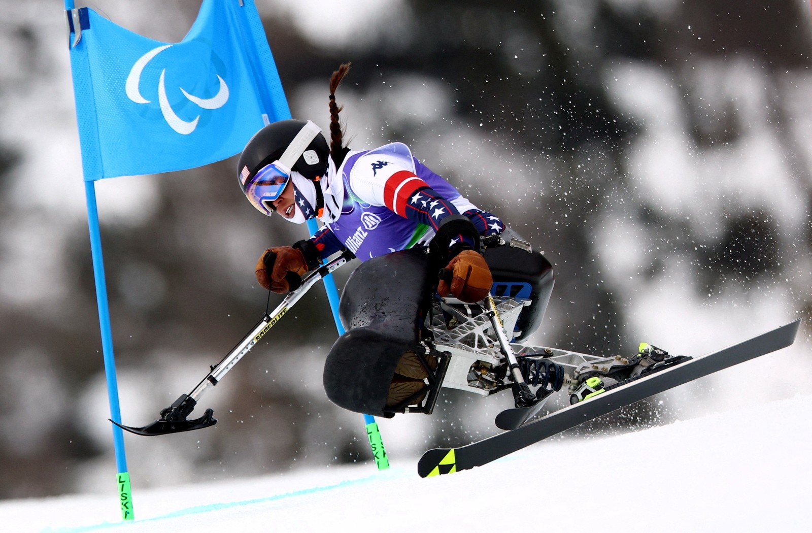 A seated para-Alpine racer skis down a course.