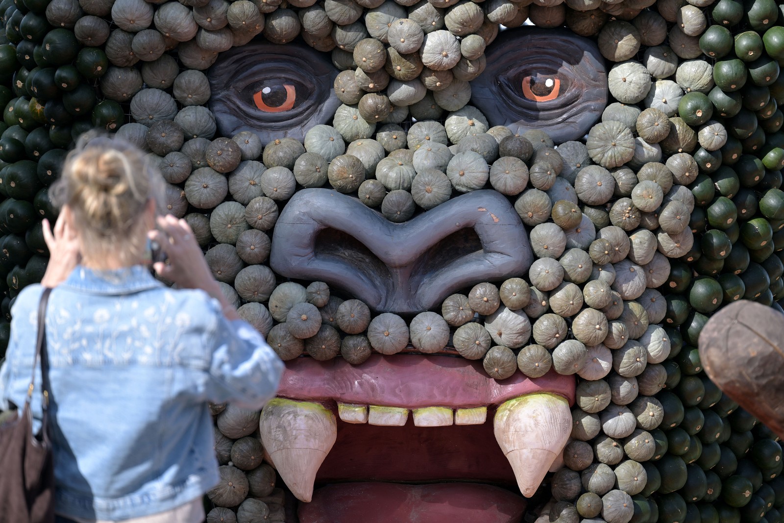 A person takes a photo of a large King Kong figure made of pumpkins.