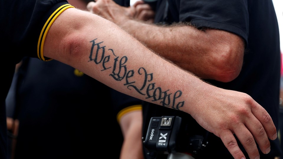 A person's arm has a tattoo that says "We The People"