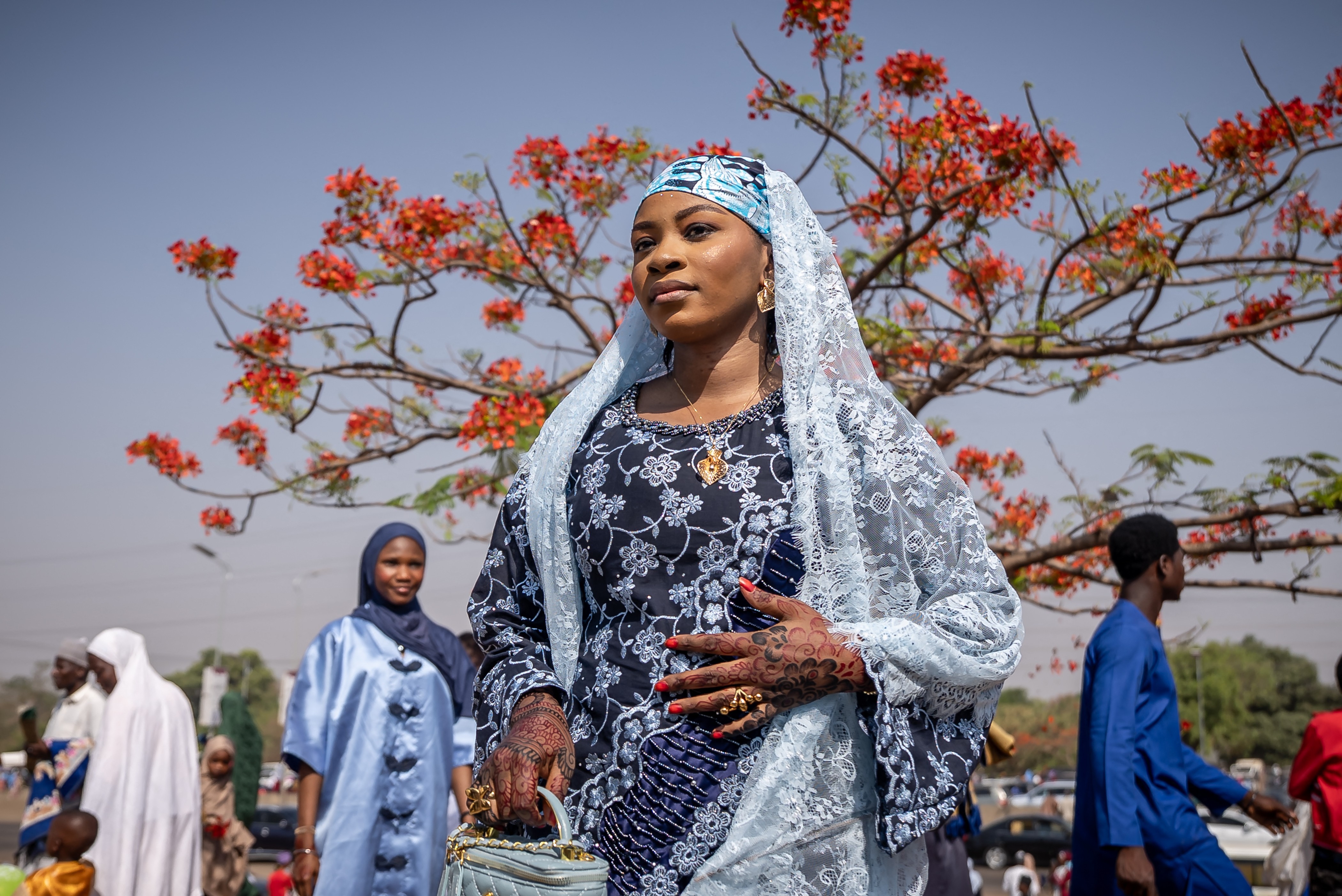 A person poses for a photo beneath a small tree.