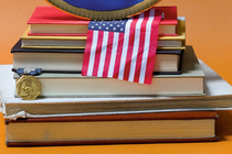 detail of photo of stack of books, American flag, medal and plate from Howard University on orange background