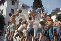 Fraternity brothers throw water at each other using buckets.