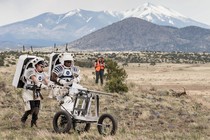 NASA astronauts push a tool cart loaded with lunar tools through the San Francisco Volcanic Field north of Flagstaff, Arizona, as they practice moonwalking operations for Artemis III.