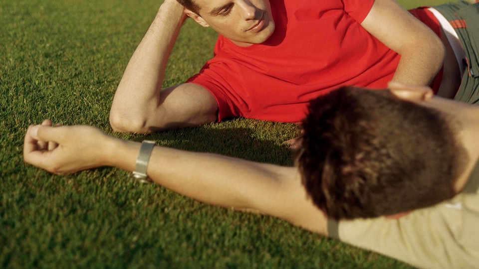 two men lying in the grass facing each other