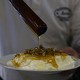 A person drizzling honey on a bowl of yogurt