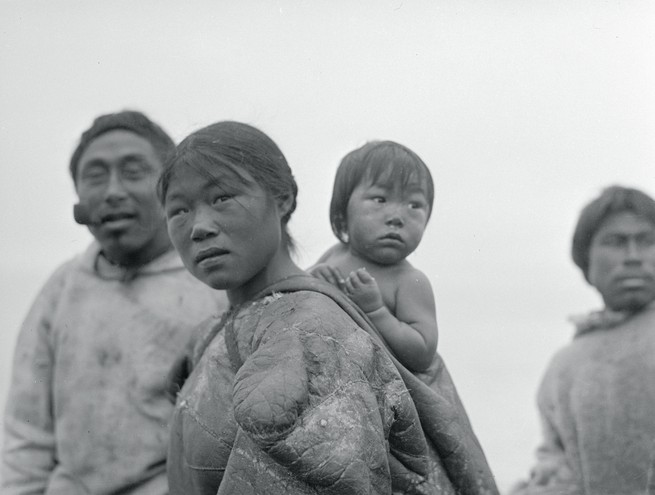 Portrait of Eskimo Family, a woman is seen in the foreground with her baby on her back