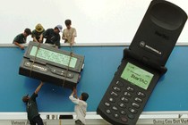 Workers hoist a giant Motorola cellphone and pager onto a billboard.