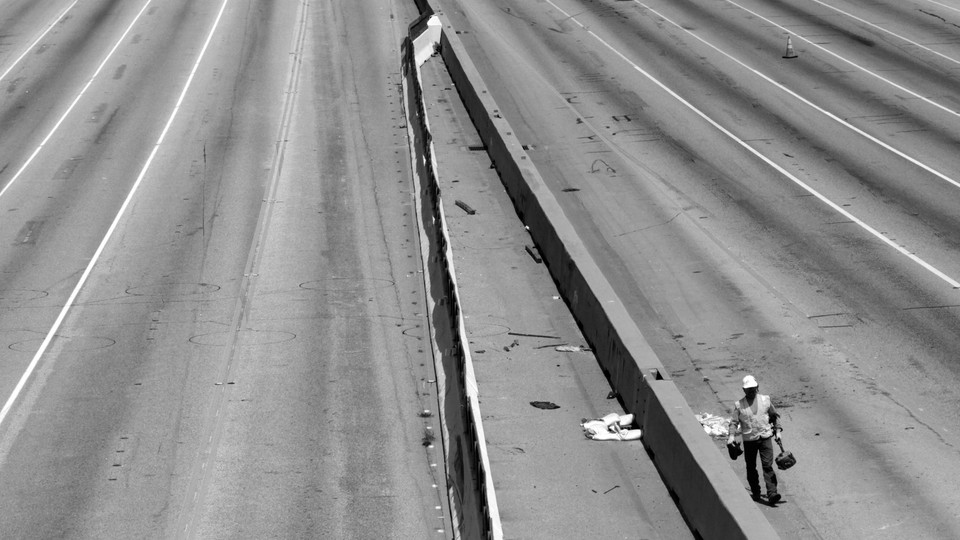 Black-and-white photo of a construction worker on an empty highway