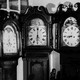 A man and woman sleep in a room full of antique clocks.