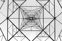 A black-and-white image of a transmission tower photographed from underneath