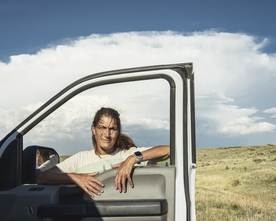 a woman stands outside her car with the door open and her hands on the window 