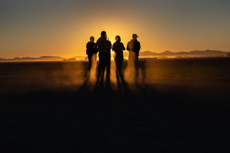 A small group of people in silhouette in an open area of land