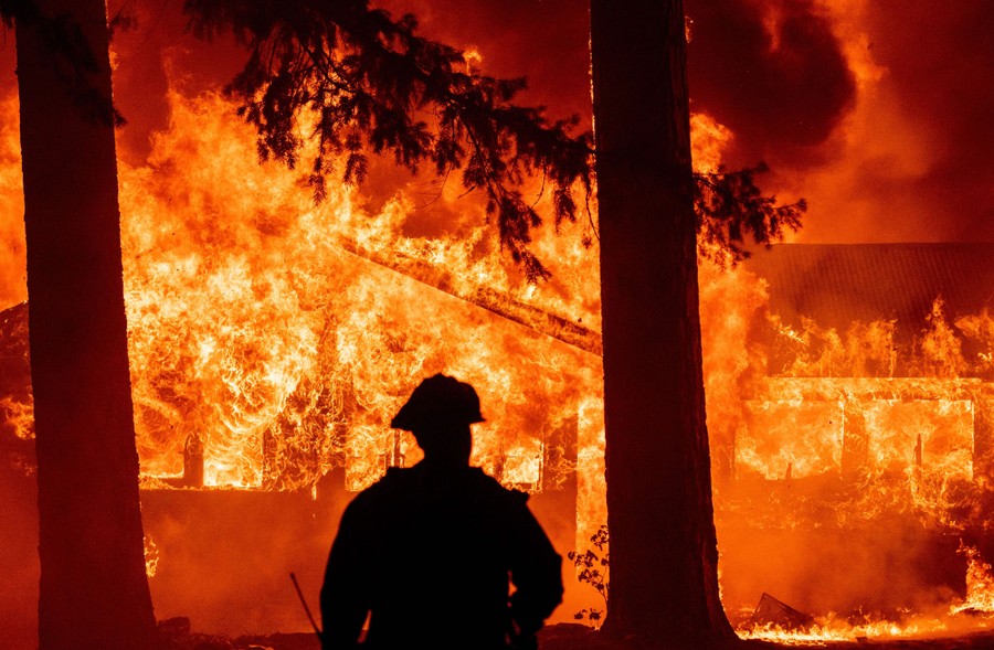 A firefighter watches as a home burns.
