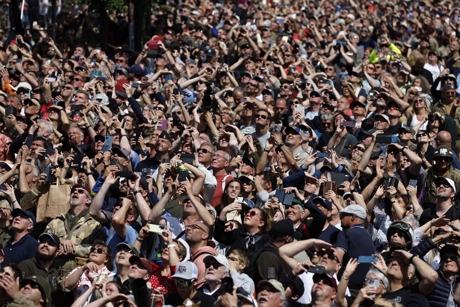 A large crowd looks up toward falling parachutes (not pictured).