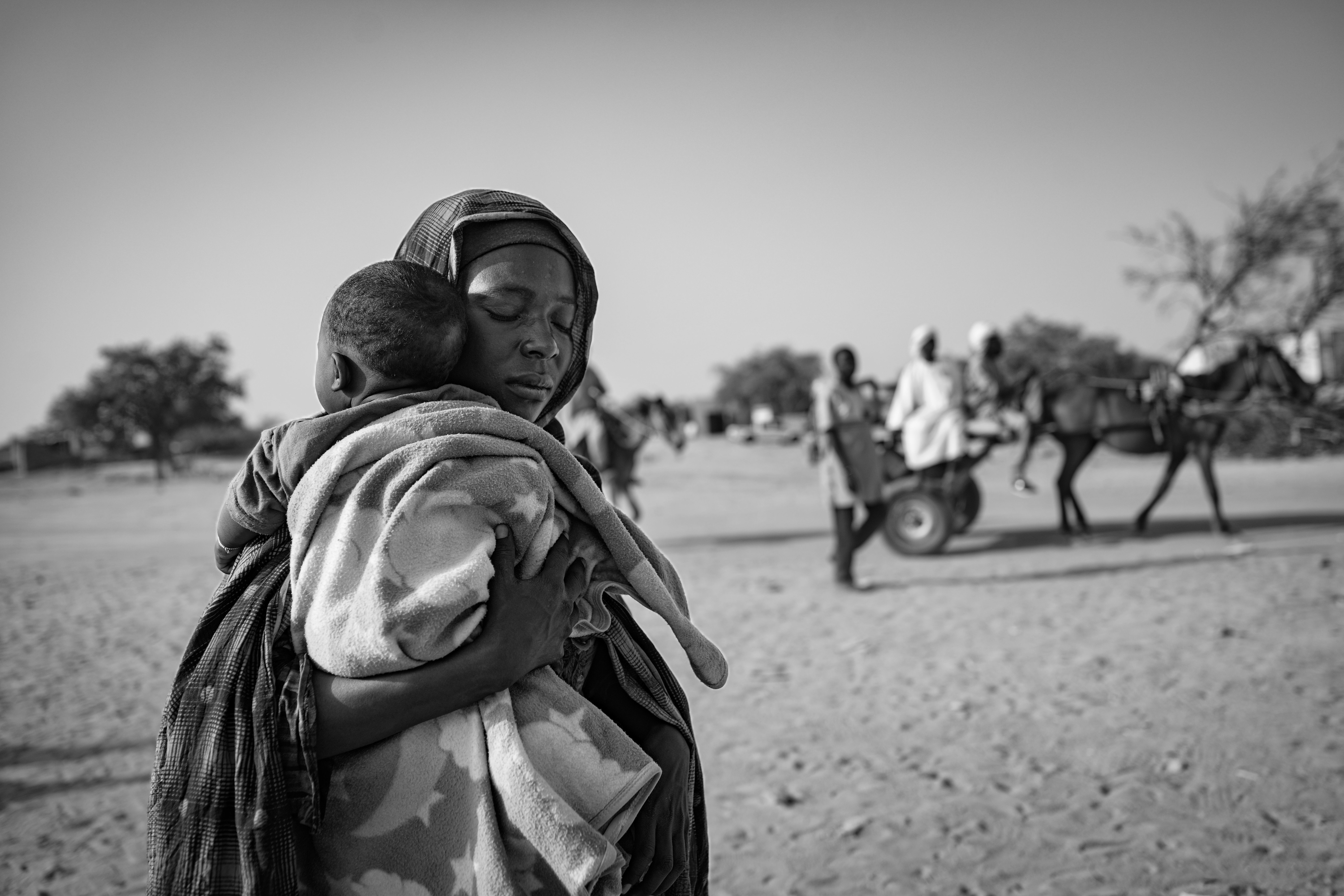 Picture of a refugee from the Zamzam camp carries her child as she arrives at the Tiné crossing into Chad.