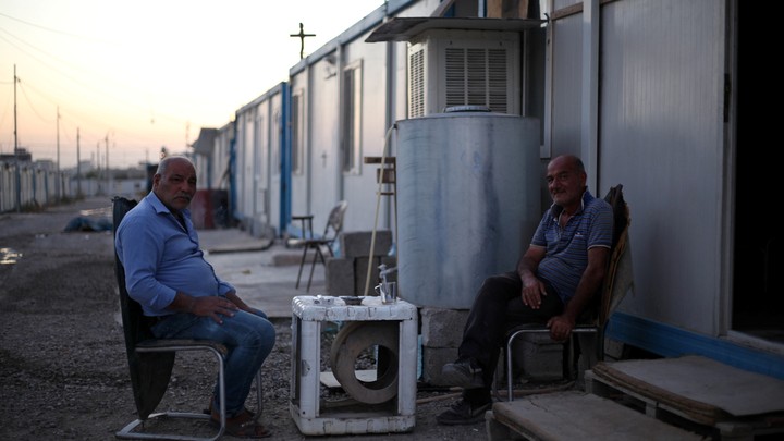 Christian men are seated outside a trailer at the Ankawa refugee camp in Erbil, Iraq, on September 12, 2018.