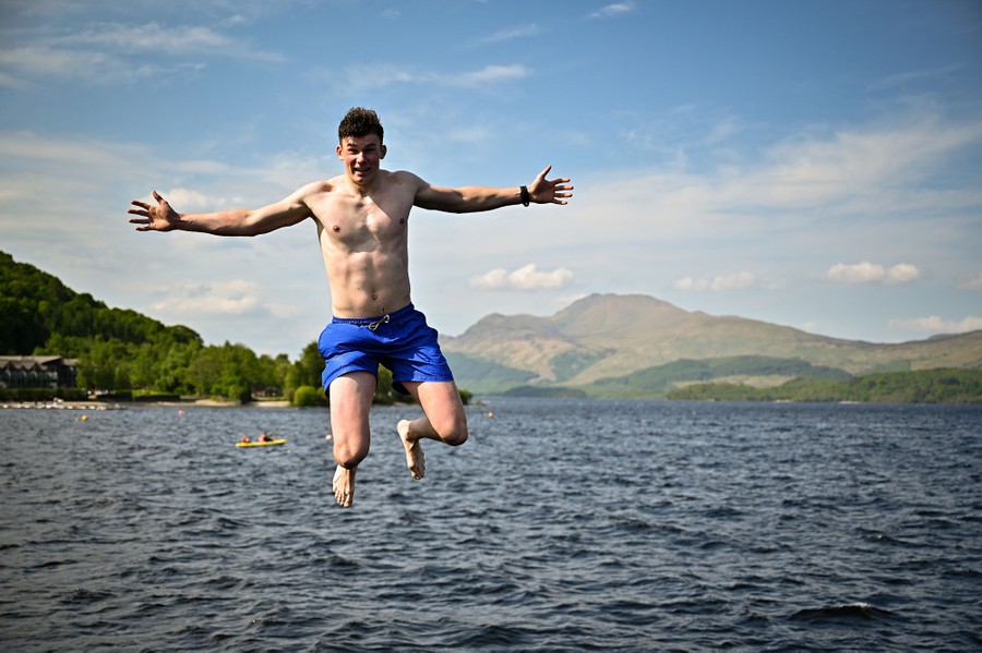 A person is seen in mid-air as they jump into a lake.