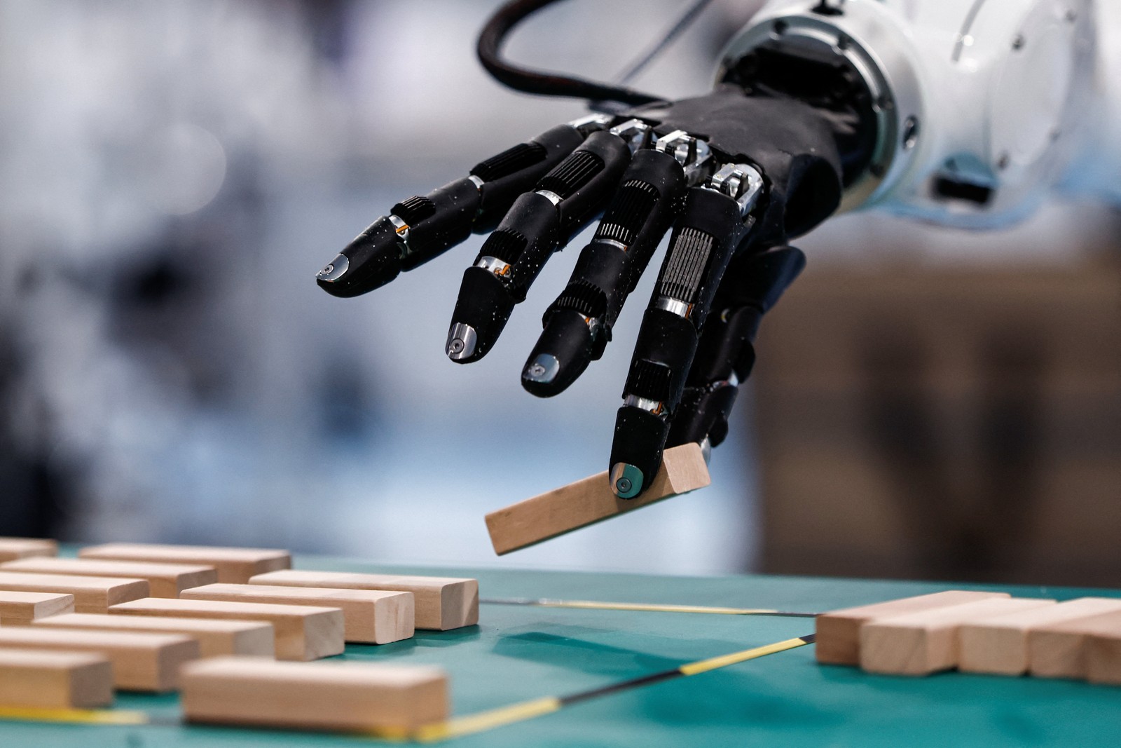A five-fingered robotic hand, holding a wooden block