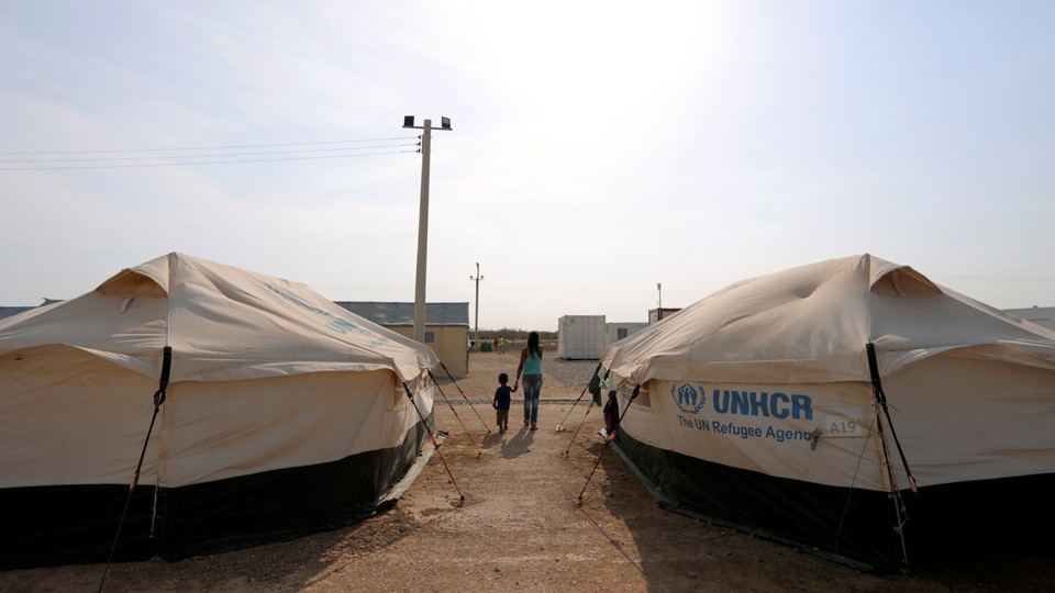A woman walks hand in hand with her son in the middle of some tents in a camp run by the United Nations refugee agency (UNHCR) in Maicao, Colombia, on May 7, 2019.