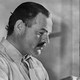 A black-and-white photo of Ernest Hemingway working at a typewriter