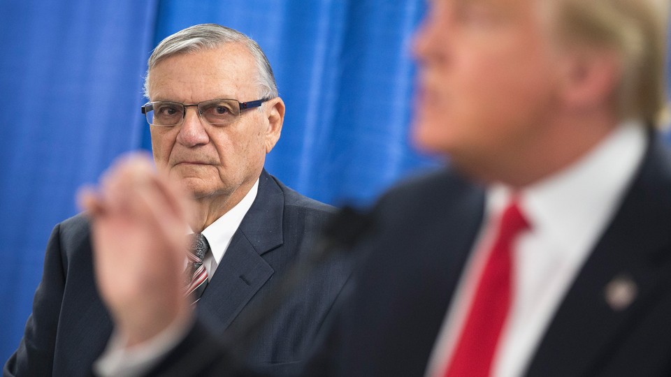 Former Maricopa County Sheriff Joe Arpaio looks on as then-presidential candidate Donald Trump speaks to reporters.