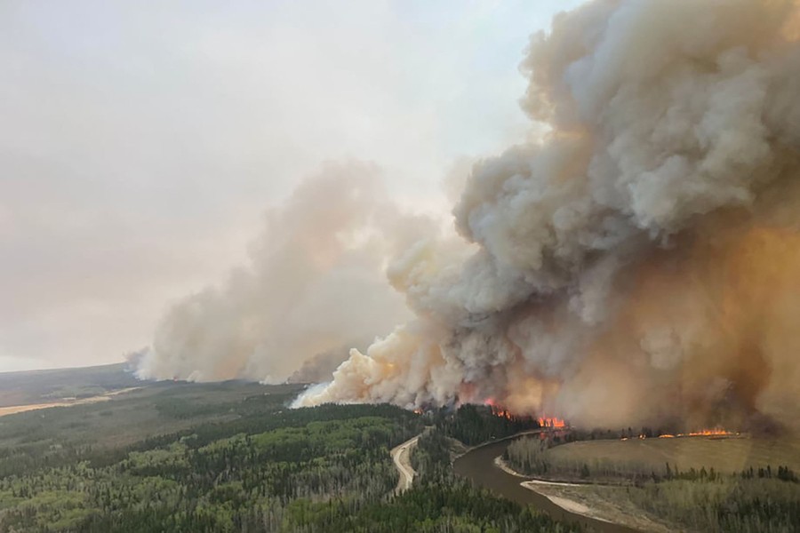 An aerial view of plumes of smoke rising from a large forest fire.