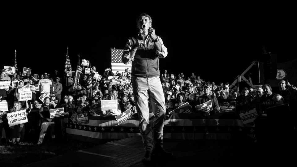 Glenn Youngkin stands on a platform amid a crowd of supporters.