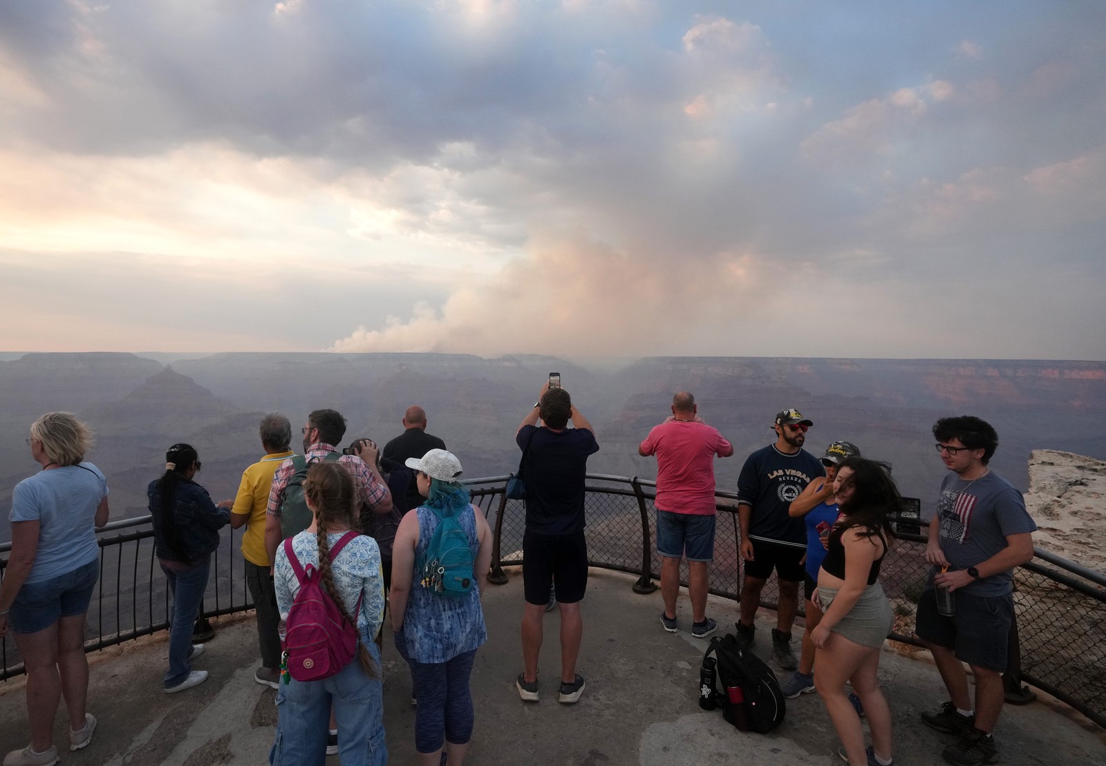 Smoke from a wildfire on the far side of the Grand Canyon is viewed by tourists at an observation point.
