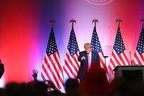Trump stands near a podium and points at the crowd in front of him