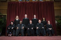 The Supreme Court justices sit in front of a red curtain for a group photo