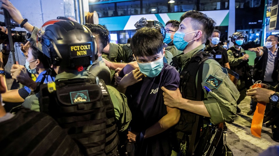 A riot police officer detains a man during a protest outside a Hong Kong shopping mall.