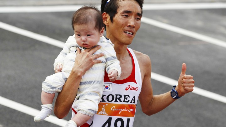 Ji Young-jun poses with his baby after winning the men's marathon at the 16th Asian Games.