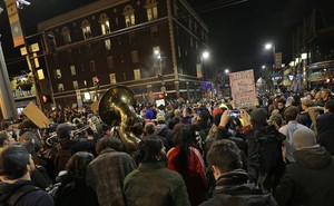 A crowd of protesters, including some with signs and one with a tuba, fill the streets in Berkeley, California, protesting a speech by Milo Yiannopoulos