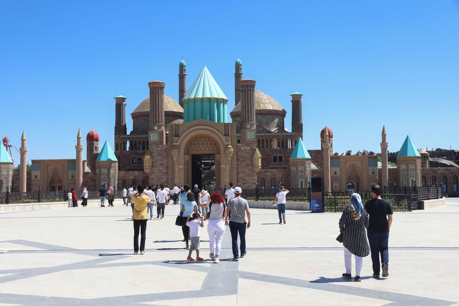 A small crowd of people walk in an amusement park.
