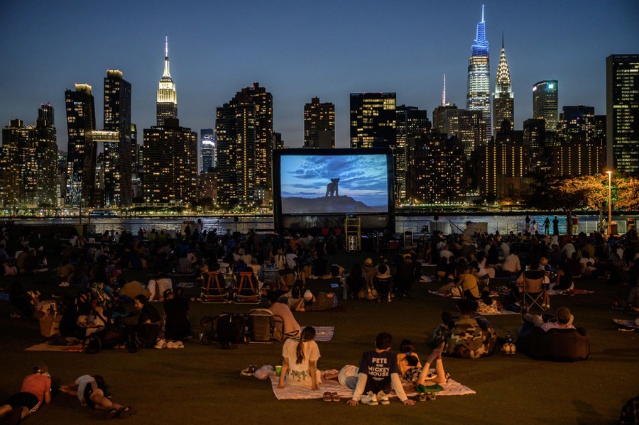People watch an outdoor screening of The Lion King in front of the Manhattan skyline.