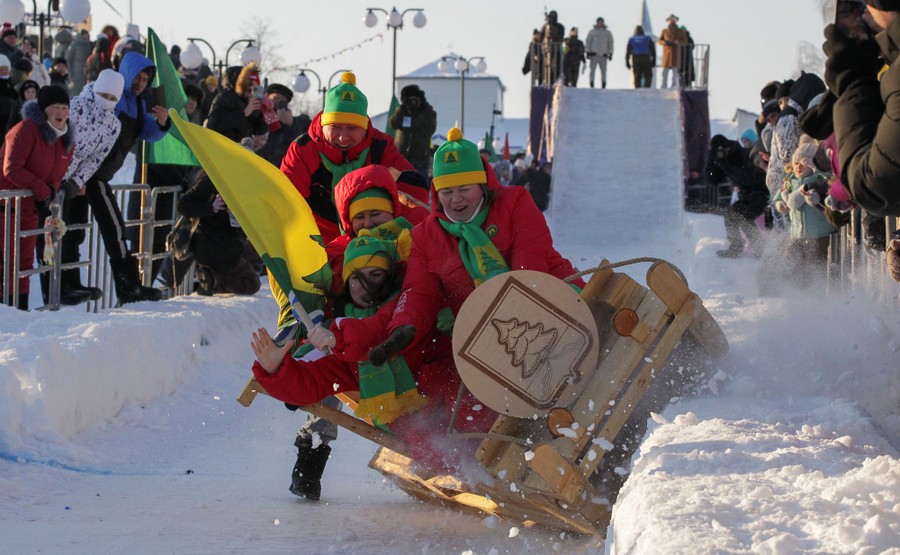 A small team of riders falls from a large sled on a straight track.