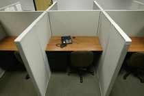 An empty office cubicle with an unplugged phone