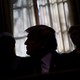 Trump sits in front of a window with his face obscured by shadows.