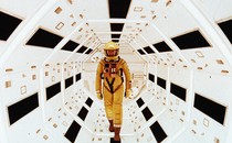 A man in a yellow spacesuit stands in a futuristic white tunnel in a scene from "2001: A Space Odyssey"