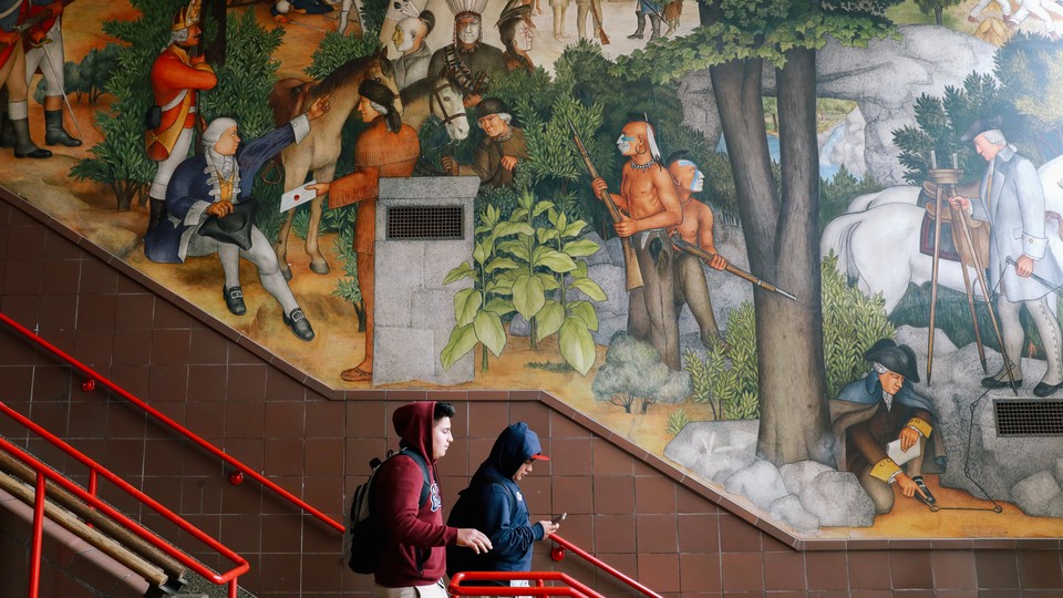 Two students walk down steps past a historical mural at George Washington High School in San Francisco.