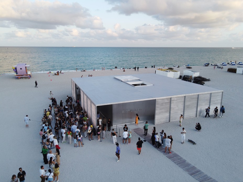 a crowd waiting to enter a building with a party on the beach